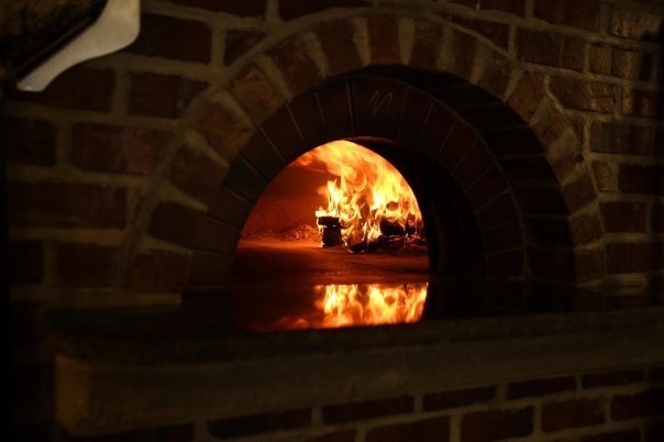 The brick clay oven at Sticks and Stones with a fire glowing inside